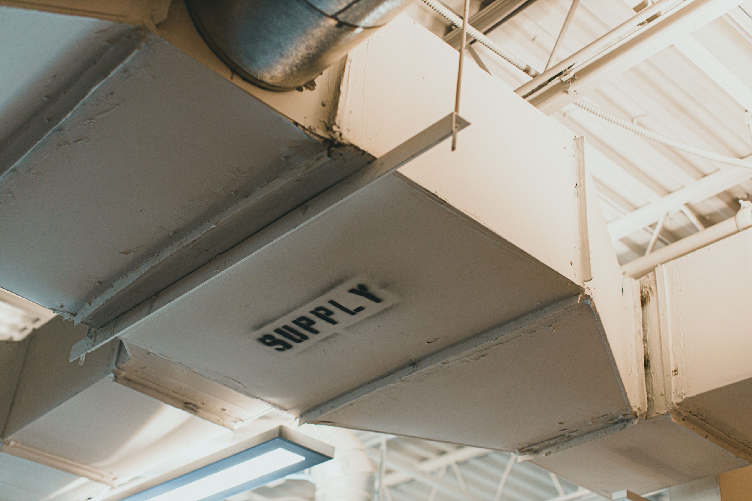 Applications Close-up view of an air duct labeled 'SUPPLY' in an industrial setting.