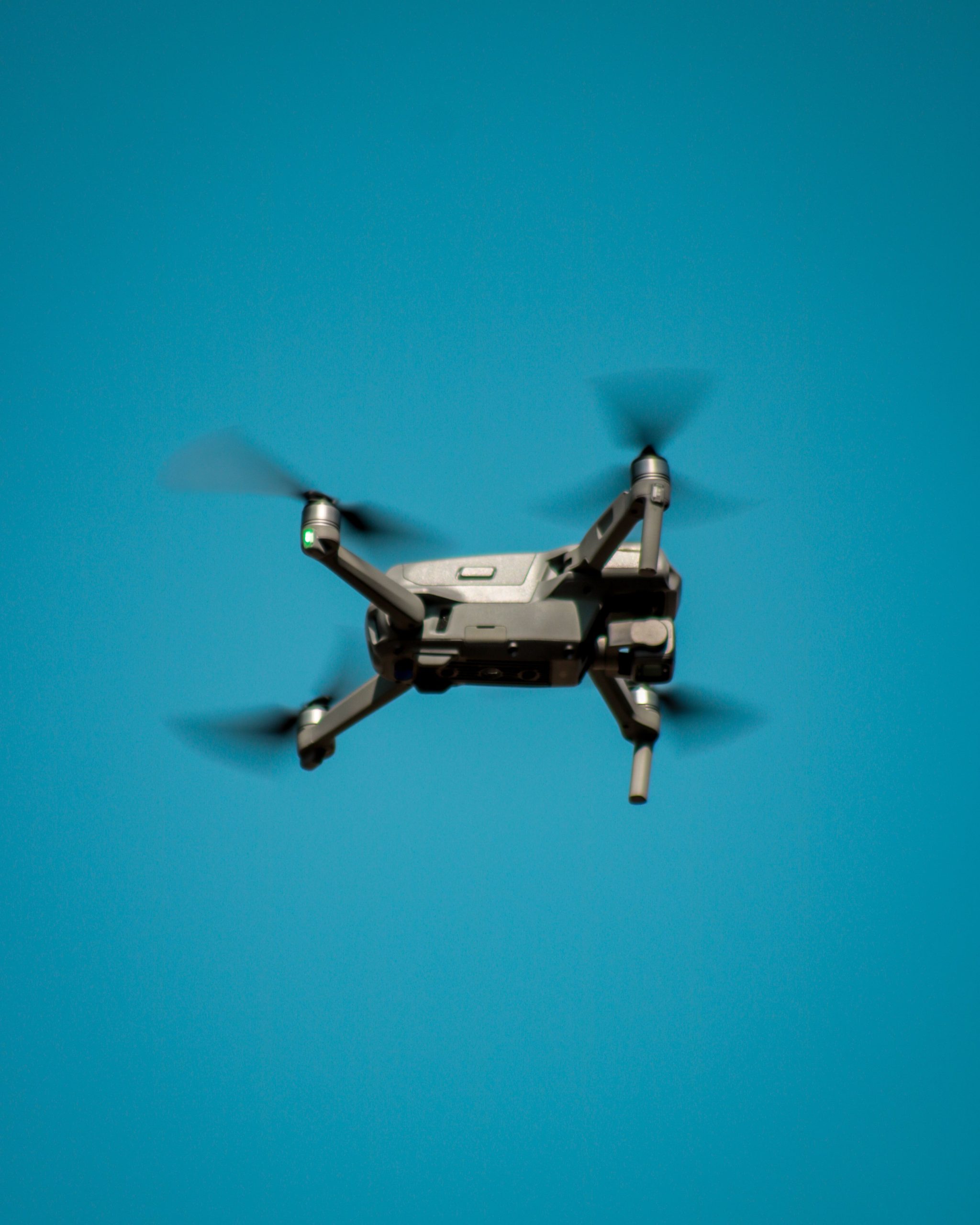 Applications A modern drone flying against a clear blue sky, showcasing aviation technology.